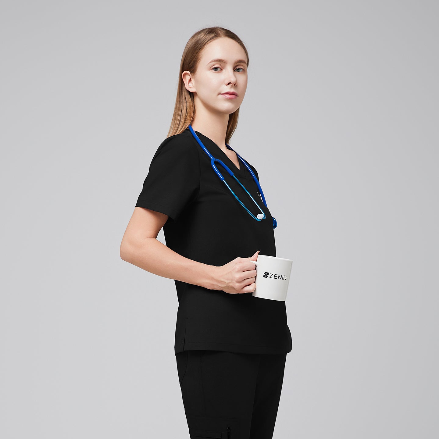 Image of Woman in a black scrub top holding a Zenir-branded mug, wearing a stethoscope and matching black scrub pants,Eco Black